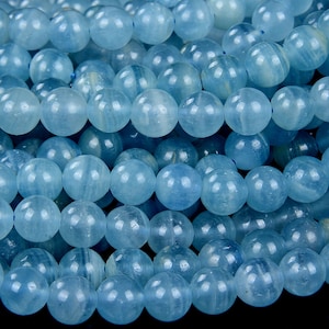 Puede incluir: Una hebra de cuentas redondas de aguamarina azul claro. Las cuentas son lisas y pulidas, con un ligero brillo.