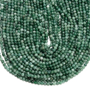 May include: A strand of green jade beads, each bead is round and smooth. The beads are strung together on a clear thread. The beads are all approximately the same size.