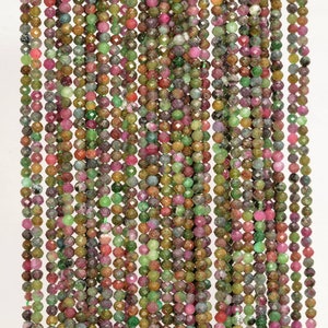 May include: A strand of faceted gemstone beads in shades of green, pink, and brown. The beads are small and round, and they are strung on a clear thread.