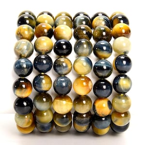 May include: A collection of round beads in shades of yellow, gold, and blue. The beads have a polished, glossy finish and are strung together. The arrangement is tightly packed, showcasing the variety of colors and patterns within the beads.
