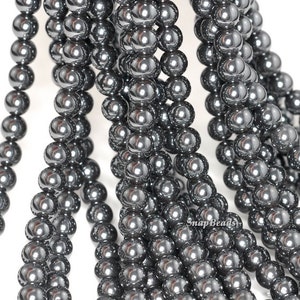 May include: A strand of round, black hematite beads. The beads are smooth and shiny, with a metallic finish.