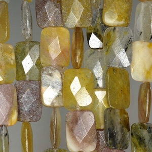 May include: A strand of faceted, rectangular gemstone beads in shades of yellow, brown, and gray. The beads have a unique, iridescent quality.