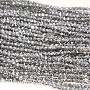 Peut inclure: Un brin de perles facettées argentées. Les perles sont petites et rondes, avec un éclat métallique.