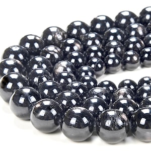 May include: A strand of black gemstone beads with a shiny, iridescent finish. The beads are round and smooth, and they are arranged in a circular pattern.