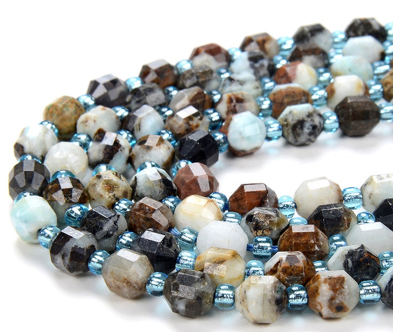 May include: A strand of faceted gemstone beads in shades of brown, white, and black, interspersed with smaller blue beads.