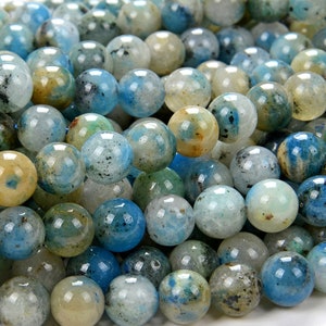 May include: A close-up of a strand of round, blue, green, and white gemstone beads. The beads have a mottled, speckled appearance.