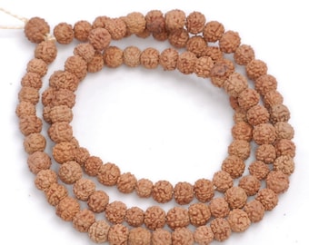 May include: A brown mala bead necklace made of Rudraksha seeds. The necklace is made of 108 beads and has a tassel at the end.