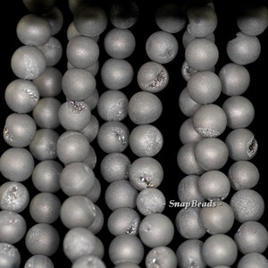May include: A strand of gray agate beads with a frosted finish. The beads are round and have a natural, irregular texture.