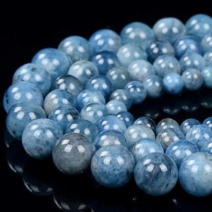 Può includere: Una collana di perle rotonde di acquamarina blu chiaro. Le perle sono lisce e lucidate, con un leggero luccichio.