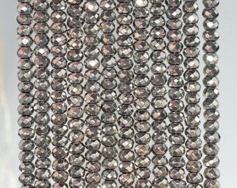 May include: A strand of faceted, silver-toned, metallic beads. The beads are round and have a slightly elongated shape. The beads are strung on a clear thread.