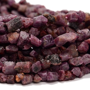 May include: A strand of rough, irregular, purple ruby gemstone beads. The beads are various sizes and shapes, with a natural, unpolished finish.
