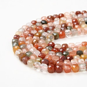 May include: A strand of faceted gemstone beads in shades of red, orange, green, and clear. The beads are square-shaped and have a polished finish.