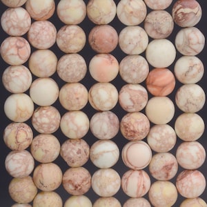 May include: A strand of round, beige, brown, and pink jasper beads. The beads have a marbled pattern and are approximately 10mm in diameter.