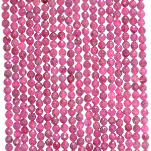 May include: A strand of pink faceted gemstone beads. The beads are small and round, with a slightly irregular shape. The beads are strung on a clear thread.