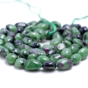 May include: A strand of green, black, and pink gemstone beads. The beads are smooth and oval-shaped.