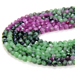 May include: A strand of green and pink gemstone beads. The beads are faceted and have a round shape.