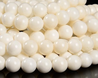 May include: A strand of white round beads made from natural shell. The beads are smooth and polished, with a slightly iridescent sheen.