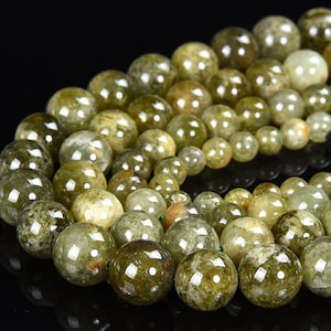 May include: A strand of round, green and yellow gemstone beads. The beads are translucent and have a speckled appearance.