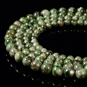 May include: A strand of green aventurine beads. The beads are round and have a speckled appearance.