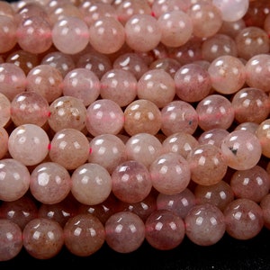 May include: A strand of translucent pink and white gemstone beads. The beads are round and have a slightly rough texture.