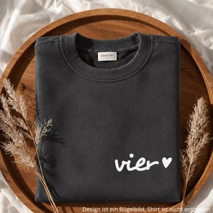 Op de afbeelding: Een antracietgrijze sweater met ronde hals voorzien van de witte tekst "vier" gevolgd door een klein wit hartsymbool aan de rechteronderkant. Het kledingstuk heeft een geribbelde halslijn en een wit binnenlabel met de merknaam Comfort Colors.