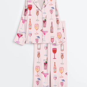 Peut inclure: Ensemble de pyjama rose clair avec un motif aquarelle de divers cocktails et verres &agrave; vin. Le haut &agrave; manches longues a une fermeture boutonn&eacute;e et le pantalon est long. L'ensemble est en mati&egrave;re douce et soyeuse.