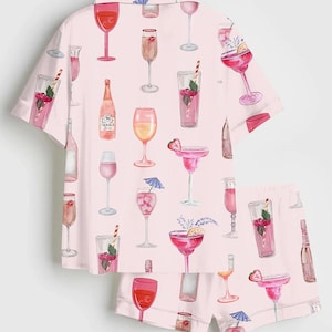 Peut inclure: Un ensemble de pyjama rose clair orn&eacute; d'un motif de verres &agrave; cocktails et de bouteilles. Le haut &agrave; manches courtes et le short pr&eacute;sentent des illustrations &agrave; l'aquarelle de boissons, notamment des margaritas, des fl&ucirc;tes &agrave; champagne et des verres &agrave; vin. L'ensemble est en tissu doux et l&eacute;ger.