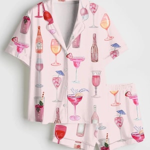 Peut inclure: Ensemble de pyjama rose clair orn&eacute; d'un motif de cocktails et de verres &agrave; vin. La chemise &agrave; manches courtes boutonn&eacute;e et le short assorti pr&eacute;sentent des illustrations de boissons avec des garnitures et des parapluies. L'ensemble est en tissu doux et l&eacute;ger.