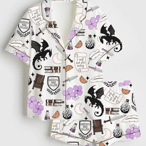May include: A white pajama set with a short-sleeved button-down shirt and shorts featuring a pattern of black dragons, swords, stacks of books, purple flowers, orange slices, and scrolls with the text I will not die today and Basgiath War College.