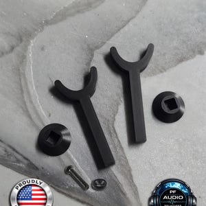 May include: Two black Y-shaped components with curved tops, two black circular bases with square center holes, one metal screw, and one small metal washer. The components are arranged on a surface with a Proudly Made in USA logo and PF Audio Solutions logo.