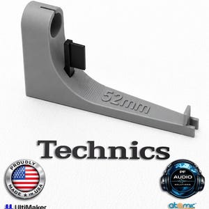 May include: A grey 3D printed Technics 52mm cartridge alignment tool featuring a vertical post with a circular opening, a small black rectangular tab, and a horizontal arm with the embossed text 52mm and a notched end for precise adjustment.