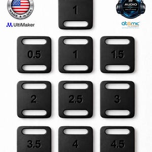 May include: A set of ten black rectangular strap adjusters with rounded corners, each featuring two horizontal slots and a central embossed number ranging from 0.5 to 4.5. The items are arranged in a grid pattern on a plain white background.