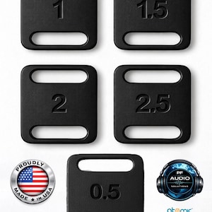 Peut inclure: Plaques de poids noires avec des coins arrondis et une découpe pour la poignée. Les poids sont étiquetés 0,5, 1, 1,5, 2 et 2,5. L'image comprend également un emblème "Proudly Made in USA" et des logos.
