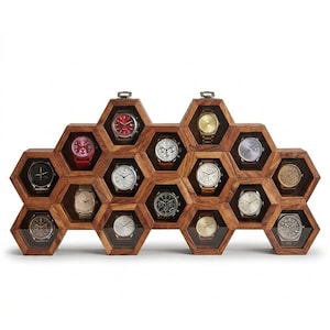 Pode incluir: Um expositor de relógios em madeira com uma estrutura em favo de mel com catorze compartimentos hexagonais individuais. Cada compartimento contém um relógio de pulso com mostradores de várias cores, incluindo vermelho, preto, prata, ouro e branco.