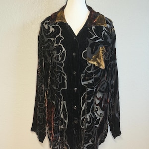 May include: A long-sleeve button-down shirt featuring a black velvet burnout pattern with floral motifs and accents of deep bronze and brown. The garment includes a pointed collar, a single chest pocket, and a front button closure on a mannequin.