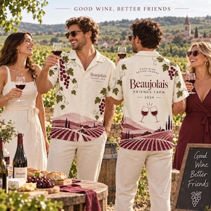 May include: A cream-colored short-sleeve button-down shirt featuring a vineyard landscape print with grapevines, clusters of red grapes, and the text "Beaujolais FRIENDS CREW 2024" on the back, along with two wine glasses clinking together.