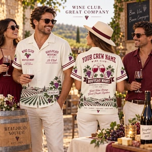 Op de afbeelding: Een crèmekleurig overhemd met korte mouwen, voorzien van een wijngaardlandschap aan de zoom, afbeeldingen van rode en groene druiventrossen en tekst waaronder "Wine Club", "Beaujolais Nouveau" en "Your Crew Name" in rode en zwarte letters.