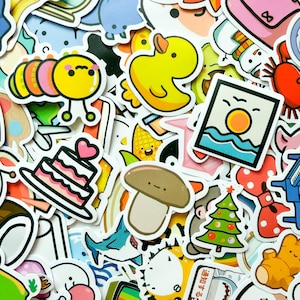 May include: A collection of colorful die-cut stickers featuring various cartoon illustrations including a yellow rubber duck, a pink and yellow caterpillar, a layered cake with a heart, a brown mushroom, a green Christmas tree, and a sunset.