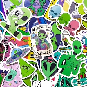May include: A selection of colourful alien-themed stickers. The stickers depict various green, blue, and pink aliens in different poses, some with UFOs and the text "Believe in Yourself". The stickers are on a white background.