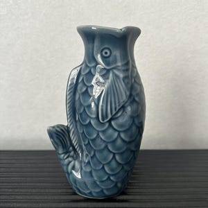 May include: A trio of cream-glazed ceramic mugs, each adorned with a hand-painted floral pattern in blue, green, and yellow. The mugs have a rounded form and a handle, perfect for enjoying a warm beverage.