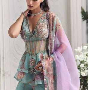 Peut inclure: Ensemble turquoise avec un haut p&eacute;plum brod&eacute; de motifs floraux et un d&eacute;tail corset transparent, assorti &agrave; un pantalon palazzo. Une &eacute;charpe lavande transparente avec garniture florale et un collier de perles compl&egrave;tent le look. Id&eacute;al pour les &eacute;v&eacute;nements formels.