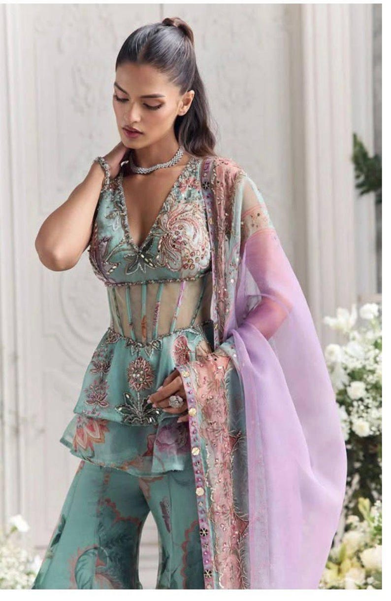 Peut inclure: Ensemble turquoise avec un haut p&eacute;plum brod&eacute; de motifs floraux et un d&eacute;tail corset transparent, assorti &agrave; un pantalon palazzo. Une &eacute;charpe lavande transparente avec garniture florale et un collier de perles compl&egrave;tent le look. Id&eacute;al pour les &eacute;v&eacute;nements formels.