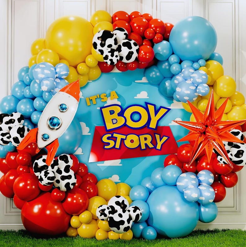 May include: A colorful balloon arch with a "Boy Story" theme. The arrangement includes red, yellow, blue, and black and white cow-print balloons. A rocket ship and star-shaped balloon add to the festive decor.