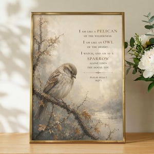 Puede incluir: Una impresión artística enmarcada que muestra un gorrión marrón posado en una rama sobre un paisaje de tonos apagados. El texto dice: I AM LIKE A PELICAN OF THE WILDERNESS: I AM LIKE AN OWL OF THE DESERT. I WATCH, AND AM AS A SPARROW ALONE UPON THE HOUSE TOP. PSALM 102:6-7 (KJV).
