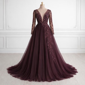 May include: A full-length, burgundy evening gown with a plunging neckline and long sleeves. The bodice and sleeves are adorned with detailed floral embroidery. The skirt is made of layered, sheer fabric, creating a flowing shape. The dress is displayed on a mannequin.