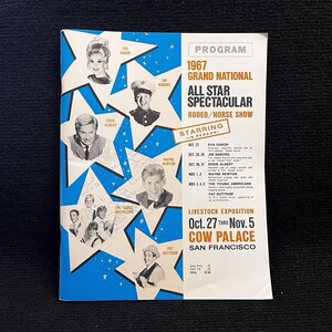 May include: A vintage program for the 1967 Grand National All Star Spectacular Rodeo/Horse Show. The program features portraits of performers like Eva Gabor, Jim Nabors, and Eddie Albert, set against a blue and white star design. The event took place at the Cow Palace in San Francisco.