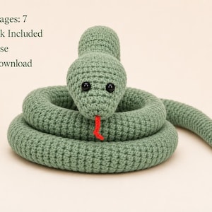 Pode incluir: Uma cobra de crochê verde-sálvia com olhos de contas pretas e língua de fio vermelho. O texto na imagem diz: Pattern Pages: 7, Video Link Included, Easy to Use, Instant Download. A cobra está enrolada em formato circular num fundo claro.