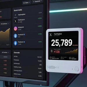 May include: A curved computer monitor displaying a social analytics dashboard with graphs and data, alongside a small white digital follower counter device mounted on an adjustable black arm, showing the number 25,789 and the text Tech Explore.
