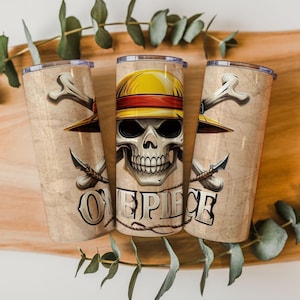 May include: Three beige stainless steel tumblers with a skull wearing a yellow hat and the text "ONE PIECE". The tumblers also feature crossed bones and swords.