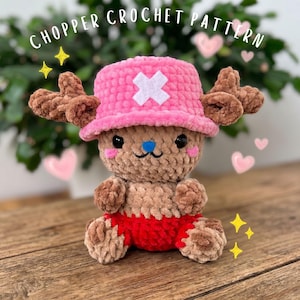 May include: A crocheted plush toy of a cartoon character, with a pink hat and white cross, brown antlers, and red shorts. The plush is brown and tan with black eyes and a blue nose. The text "CHOPPER CROCHET PATTERN" is at the top.